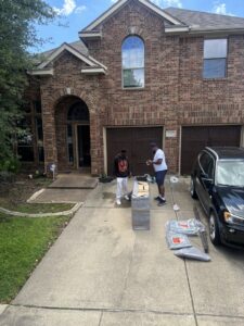 Two Advantage Express Movers team members preparing to move a large, wrapped item on a residential driveway in Arlington, TX.