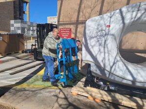 Movers using a specialized dolly to transport heavy medical equipment, demonstrating services by Peroulas Moving and Storage in Knoxville, TN