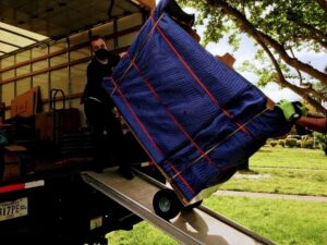 Two movers using a dolly to load a large, wrapped item onto a truck for S&P Network's Marathon Moving Solutions in Mechanicsburg, PA.