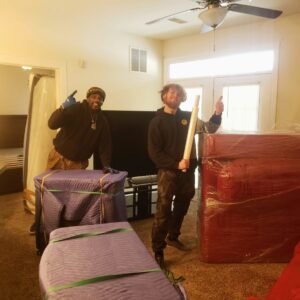 Two movers standing with carefully wrapped furniture and boxes, ready for moving by S&P Network's Marathon Moving Solutions in Mechanicsburg, PA.