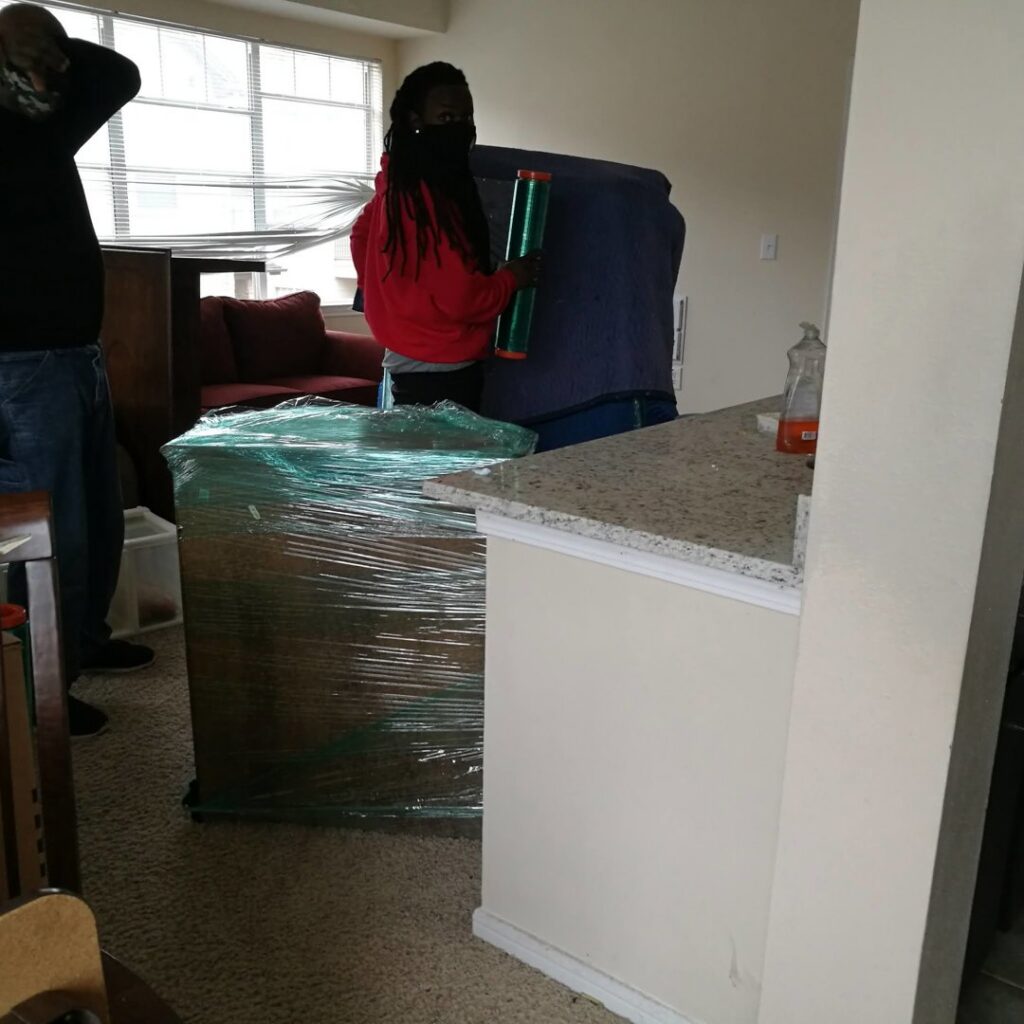 Movers from allpromovingservice wrapping furniture and preparing items inside a client's home in San Antonio, TX.