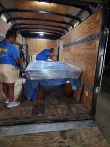 Two movers carefully wrapping a table inside a Ron's Moving truck in Little Rock, AR.