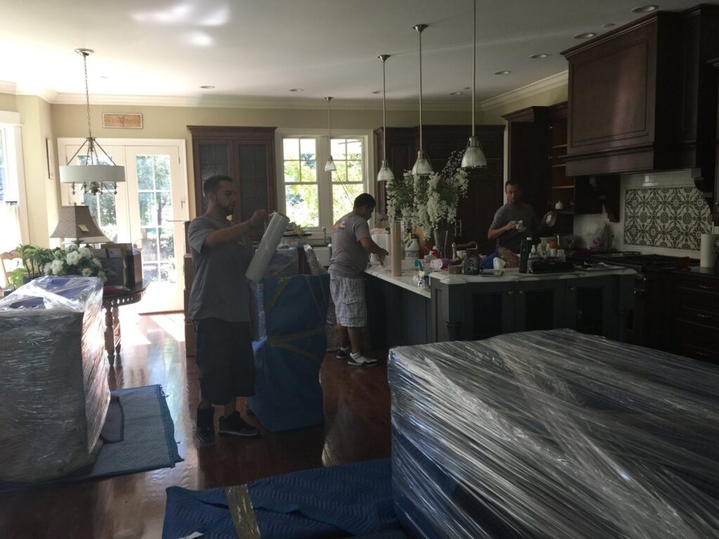TruMoving movers carefully wrapping furniture in a client's kitchen during a move in Lakewood, CO.