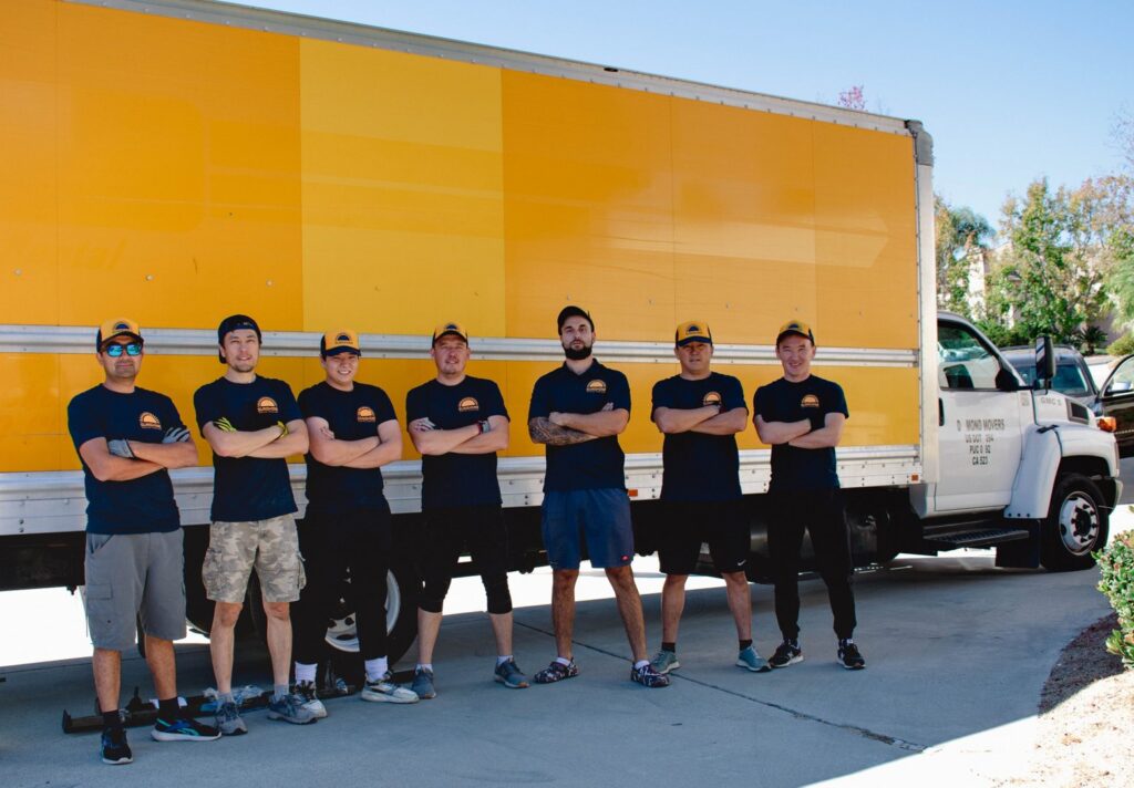 The moving crew from Sunshine Moving Services LLC in dark shirts standing in front of a moving truck in San Diego, CA.