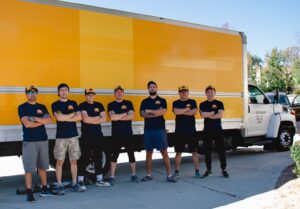 The moving crew from Sunshine Moving Services LLC in dark shirts standing in front of a moving truck in San Diego, CA.