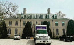 A Paradise Moving & Storage truck parked in front of a large mansion in Boston, MA.