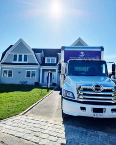A Paradise Moving & Storage truck parked in front of a residential home on a sunny day in Boston, MA.