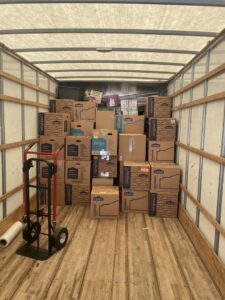 A moving truck interior filled with stacked moving boxes and a hand truck by Fatboy Slims Moving Company in Colorado Springs, CO.