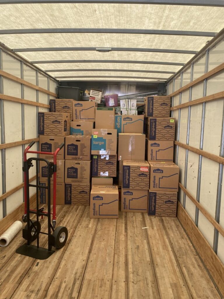 A moving truck interior filled with stacked moving boxes and a hand truck by Fatboy Slims Moving Company in Colorado Springs, CO.