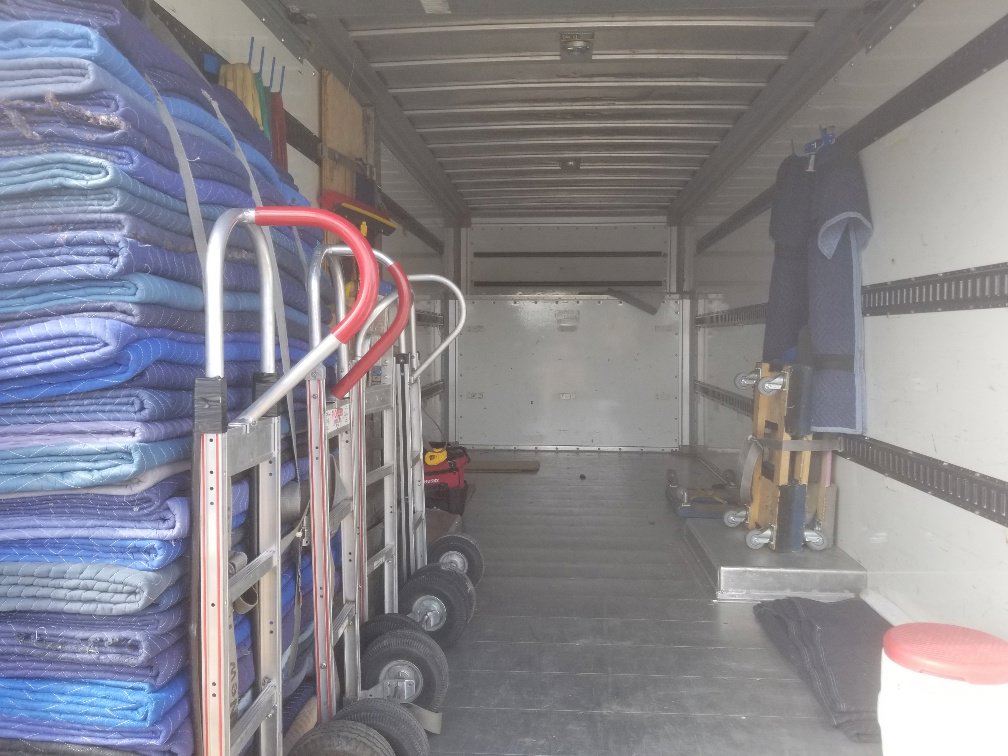 The interior of a moving truck showing neatly stacked moving blankets and hand trucks from Moving Pros LLC in Surprise, AZ.