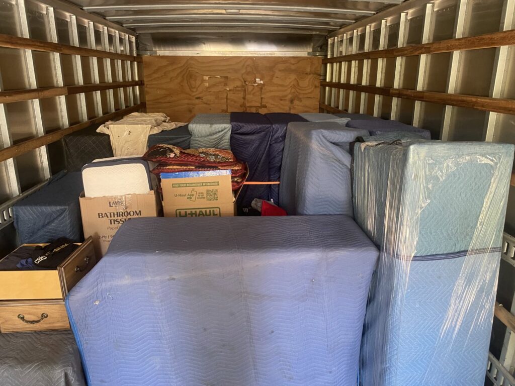 The interior of a moving truck filled with furniture wrapped in blue blankets by Rambling Man Logistics in Hildebran, NC.