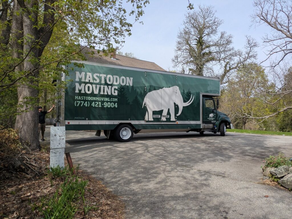 A Mastodon Moving LLC truck parked on a driveway at a residential house in Westborough, MA, ready for a move.