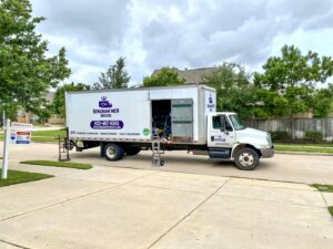 A Kingdom Men Movers truck parked on the street in front of a residential house, ready for a move in Houston, TX.