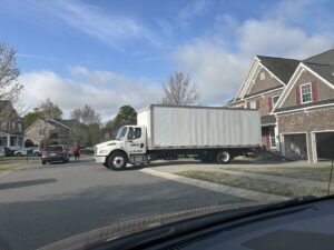A large moving truck parked in front of a residential house with a ramp extended by Rambling Man Logistics in Hildebran, NC.