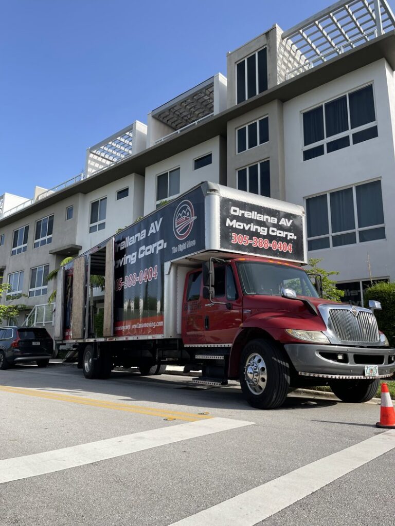 An Orellana AV Moving Corp. truck parked outside a modern residential building in Miami, FL, ready for a move.