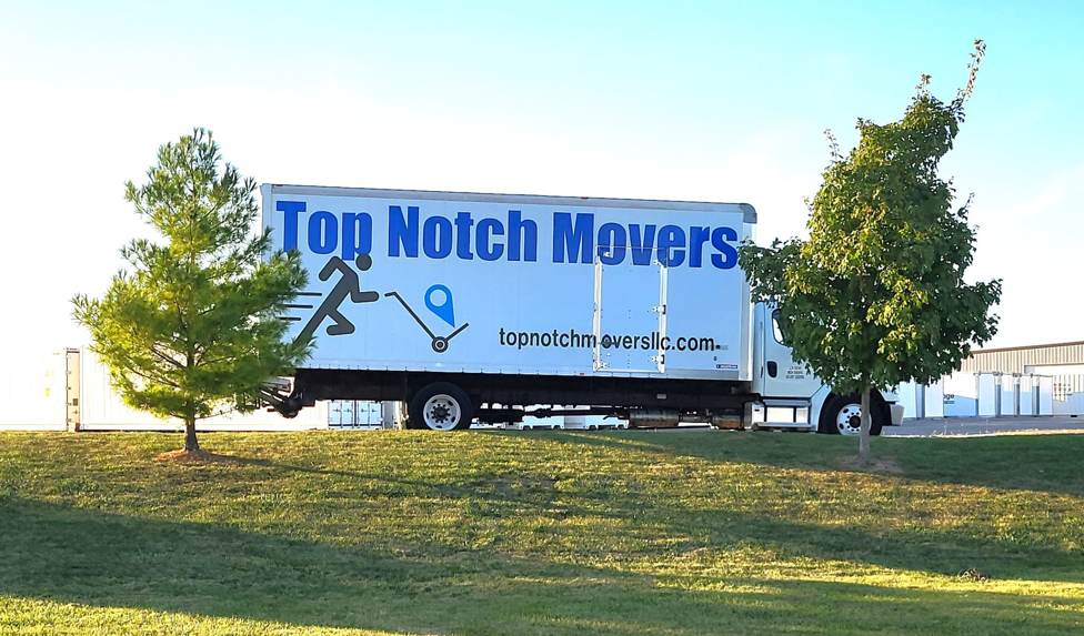 A Top Notch Movers truck parked on a grassy area with trees, ready for service in Lauderhill, FL.