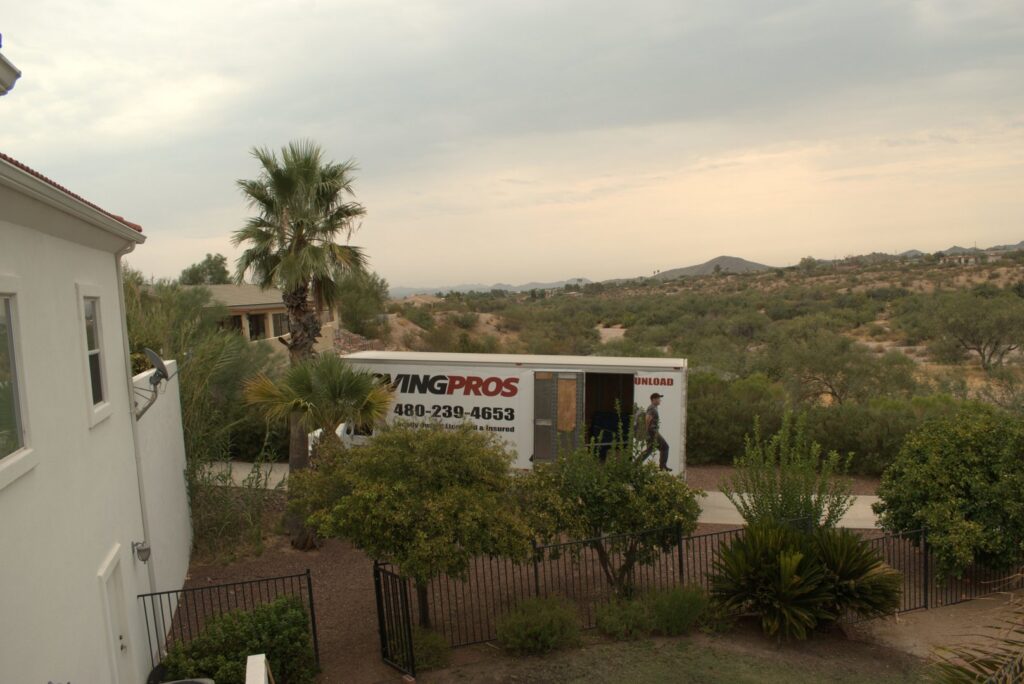 A Moving Pros LLC truck parked outside a residential house in Surprise, AZ, ready for a move.