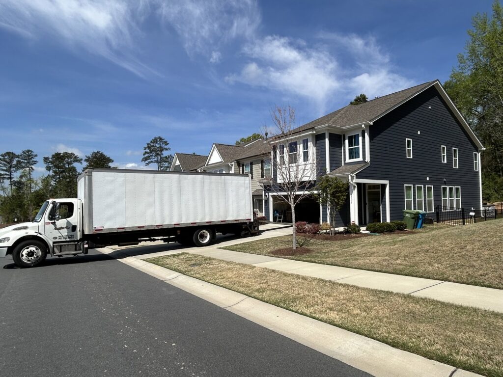 A large moving truck parked in front of townhouses, ready for a job by Rambling Man Logistics in Hildebran, NC.