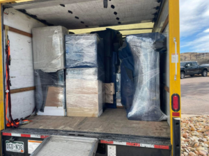 A moving truck with its ramp down, loaded with wrapped furniture and boxes by Piece by Peace Moving in Colorado Springs, CO.