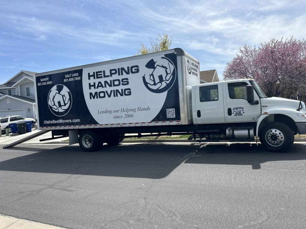 A Helping Hands Moving & Maids truck with its ramp extended, ready for loading or unloading in Salt Lake City, UT.