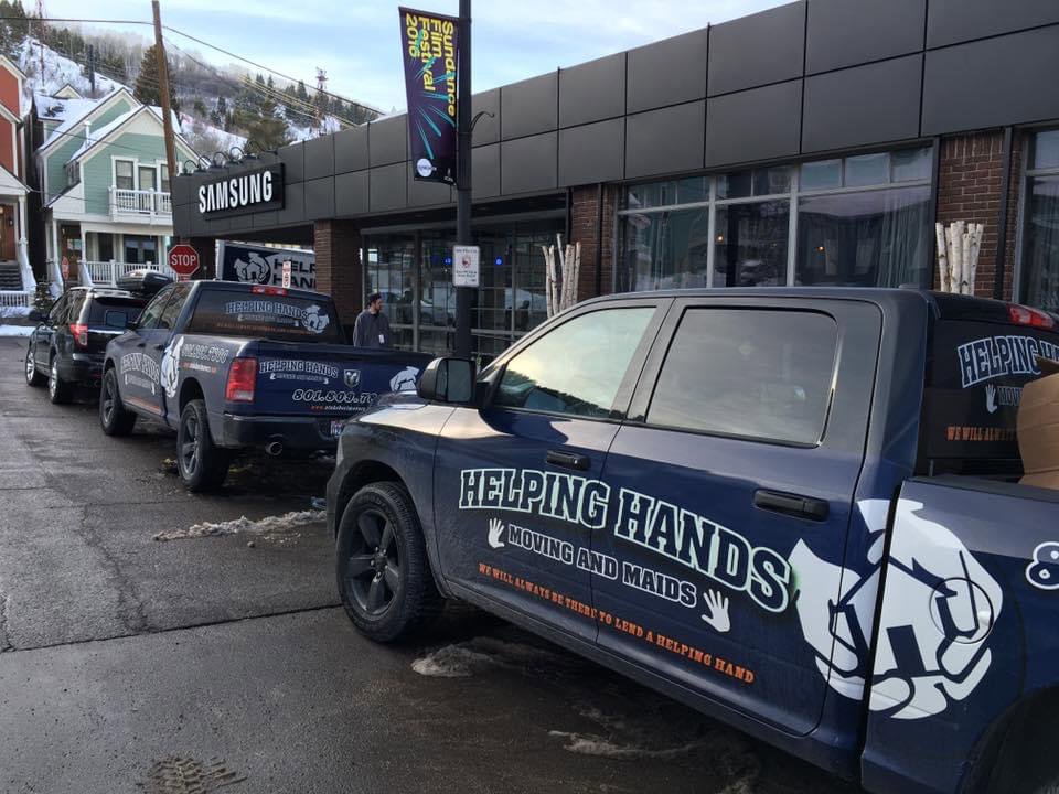 A Helping Hands Moving & Maids truck with its ramp extended on a residential street, ready for a moving job in Salt Lake City, UT.