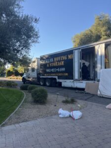 A Muscular Moving Men & Storage truck parked on a residential street with its back open, ready for loading or unloading in Phoenix, AZ.