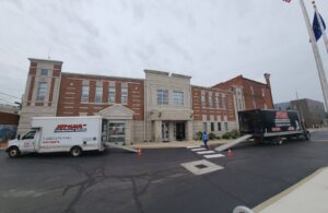 Joy Haul Professional Movers' trucks with ramps set up outside a commercial building for a business relocation in Columbia City, IN.