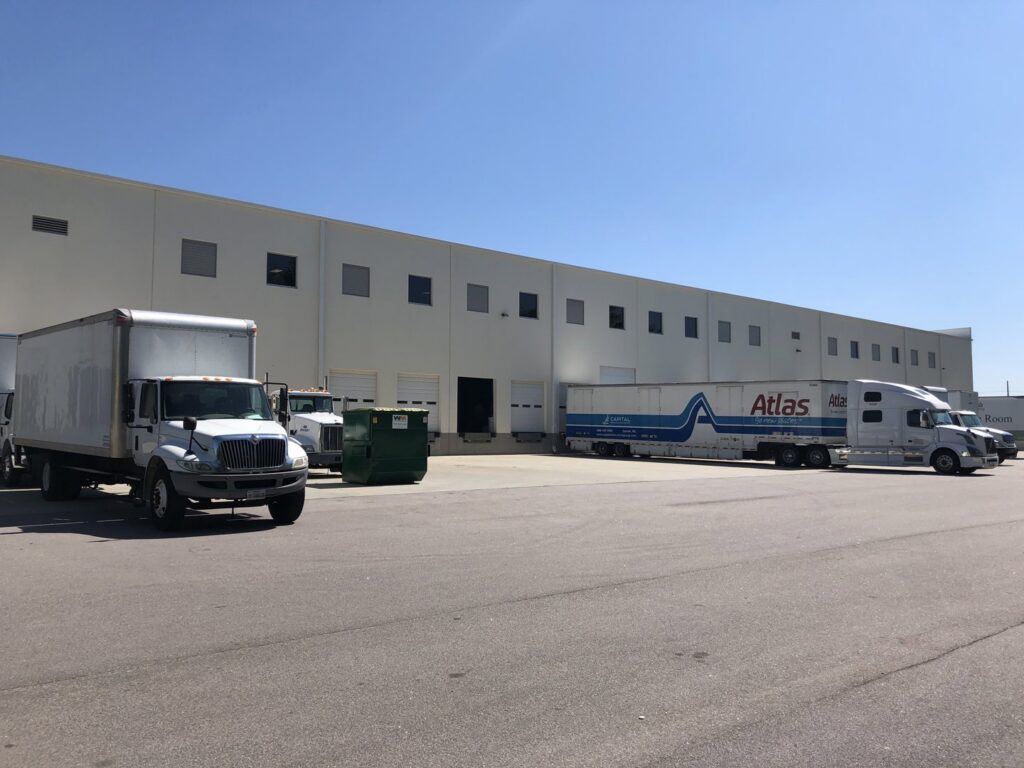 Moving trucks, including Capital Relocation Group and Atlas, parked at loading docks of a commercial building in Raleigh, NC.