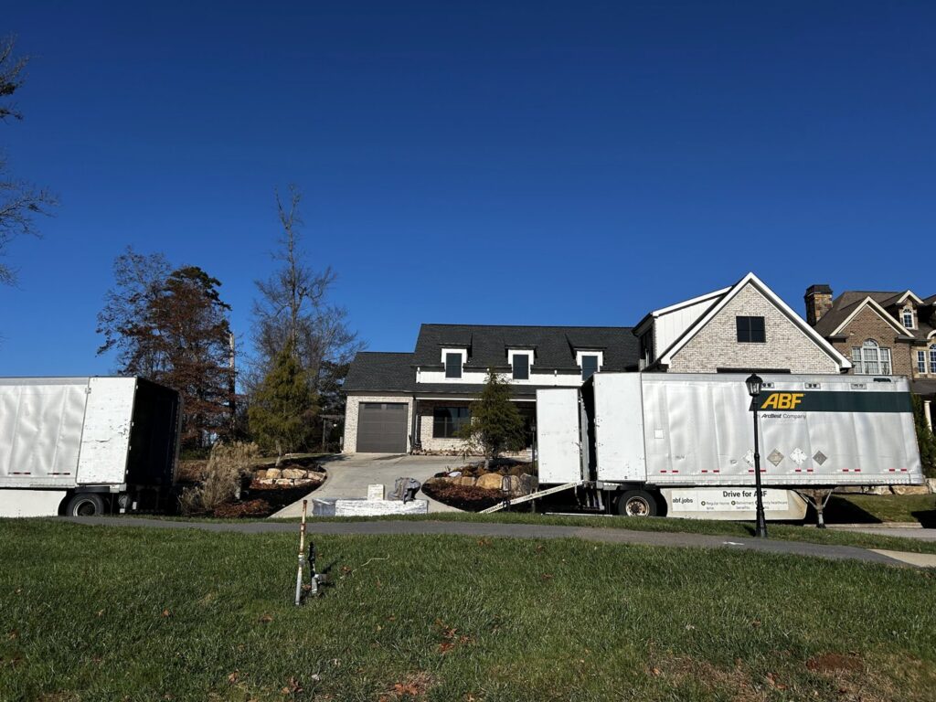 Two large moving trucks parked outside a residential house, indicating a moving job by The Knoxville Moving Co. in Knoxville, TN.