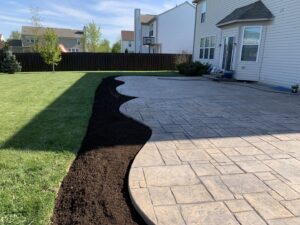 A freshly mulched garden bed with a neatly edged border next to a mowed lawn, completed by Jerman Lawn Care in Bozeman, MT.