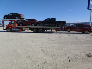 A multi-car carrier truck from Rivera Garcia Towing transporting several vehicles and towing a minivan in Omaha, NE.
