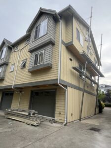 Multi-story building with yellow and gray siding under installation, showing scaffolding by Ideal Siding Winston-Salem, NC.