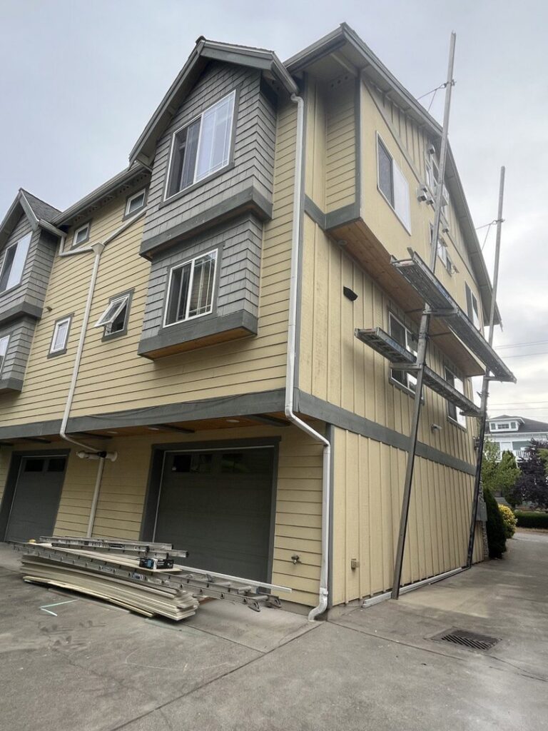 Multi-story building with yellow and gray siding under installation, showing scaffolding by Ideal Siding Winston-Salem, NC.