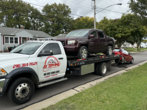 Av towing llc providing multi-vehicle towing service with a maroon pickup and a red car in Cleveland, OH.