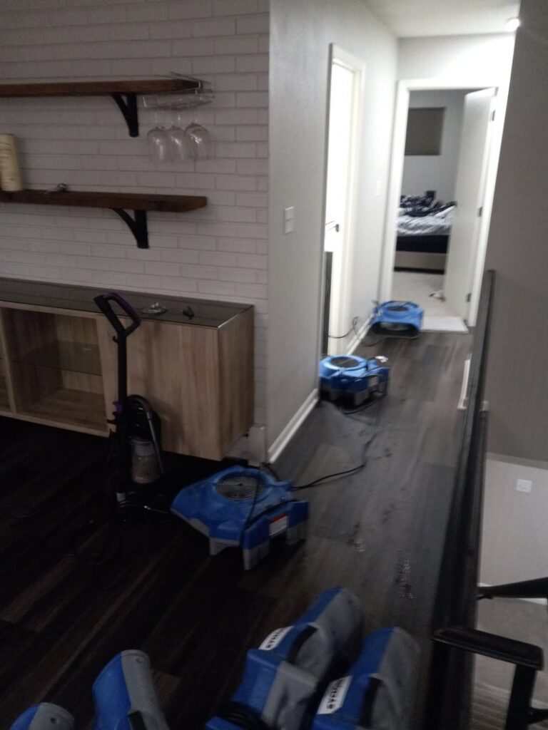Multiple air movers drying a hallway with dark wooden floors during water damage restoration by Restoration Alliance Services in Elk River, MN.
