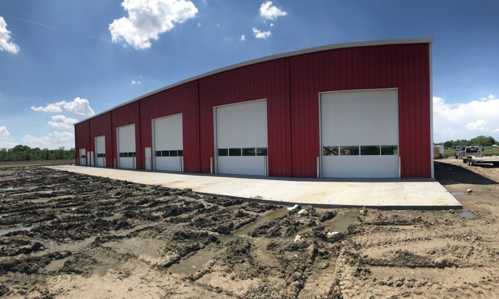 Multiple white commercial overhead doors installed on a red industrial building by Elite Door in Winchester, CA.