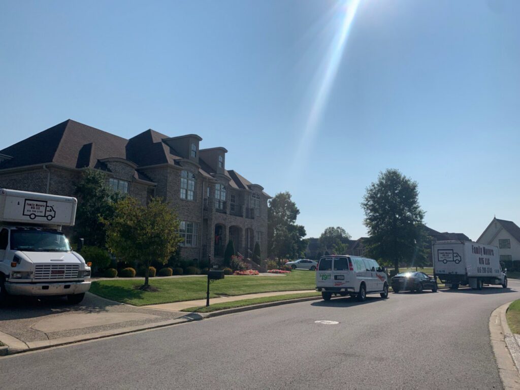 Multiple Family Movers 615 LLC trucks and a van parked on a residential street for a moving job in Goodlettsville, TN.