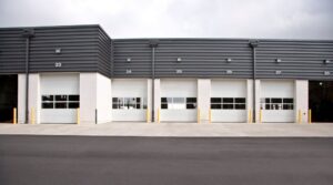 Multiple white commercial garage doors with windows installed by Overhead Door Company of Mid-Ohio Valley in Parkersburg, WV.