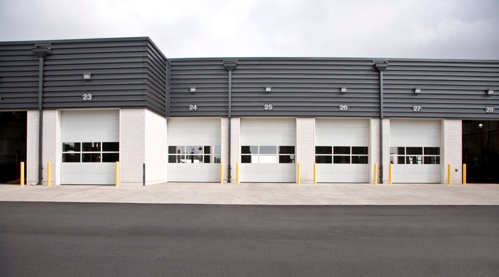 Multiple white commercial garage doors with windows installed by Overhead Door Company of Mid-Ohio Valley in Parkersburg, WV.