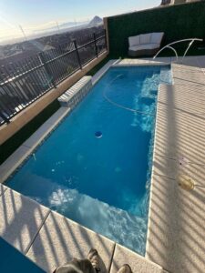A narrow swimming pool with a pool vacuum hose, indicating cleaning service by Priority Pools LV in Las Vegas, NV
