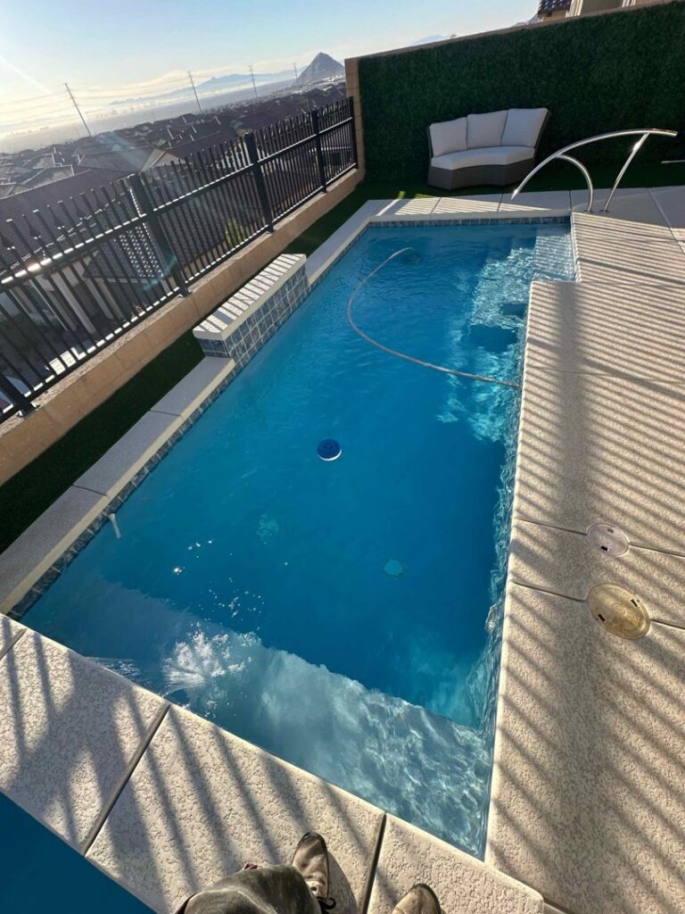 A narrow swimming pool with a pool vacuum hose, indicating cleaning service by Priority Pools LV in Las Vegas, NV