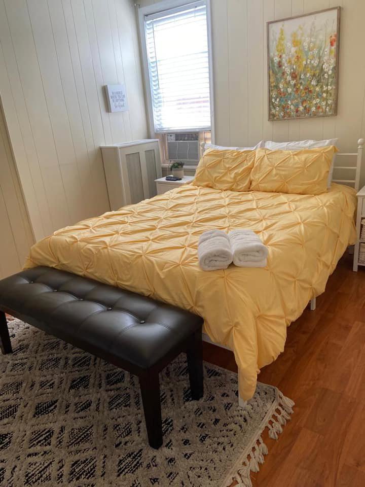 A neatly made bed with a yellow comforter and folded towels in a clean bedroom, demonstrating house cleaning services by Rivas Molina's Cleaning LLC in Dundalk, MD.
