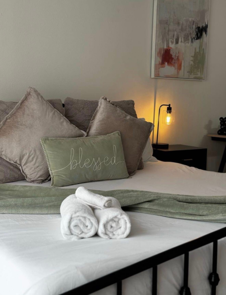 A neatly made bed with fresh, rolled towels, showcasing a cleaned bedroom by Evelyn's Cleaning Services in Huntsville, AL.