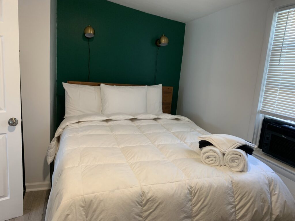 A neatly made bed with fresh, rolled towels, showcasing attention to detail by Faye Cleaning Service LLC in Ankeny, IA.