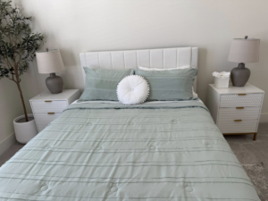 A neatly made bed with fresh linens in a clean bedroom, a service provided by Global Provisions, AR in Fayetteville, AR.