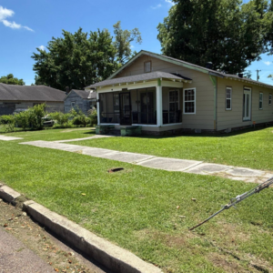 A neatly mowed front yard lawn and sidewalk, showcasing professional lawn care by Day One Landscaping in Mississippi.
