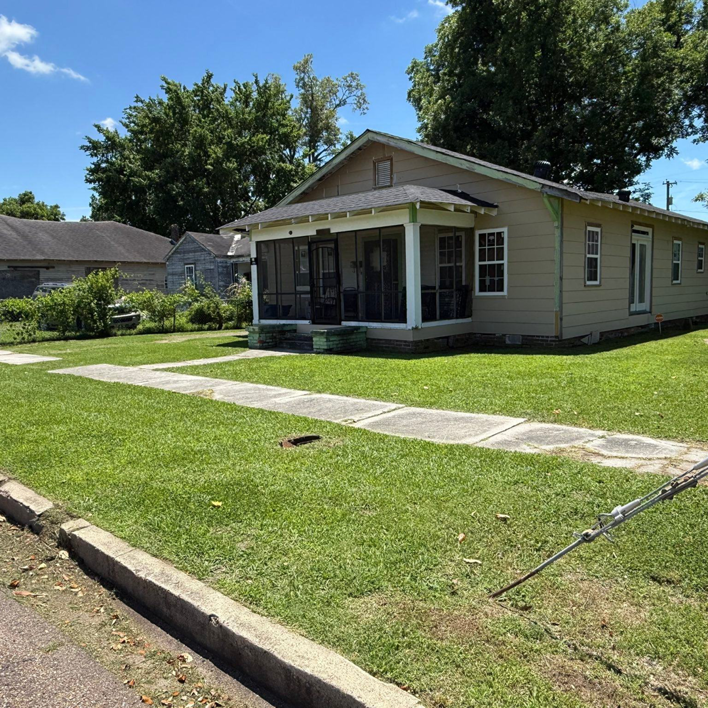 A neatly mowed front yard lawn and sidewalk, showcasing professional lawn care by Day One Landscaping in Mississippi.