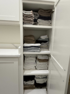 A neatly organized linen closet with folded towels and sheets, showcasing professional home organization by Global Provisions, AR in Fayetteville, AR.