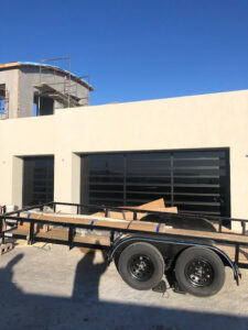 Two new black garage doors with horizontal windows installed on a house under construction by Quality-Brand Garage Doors in Rio Rancho, NM.