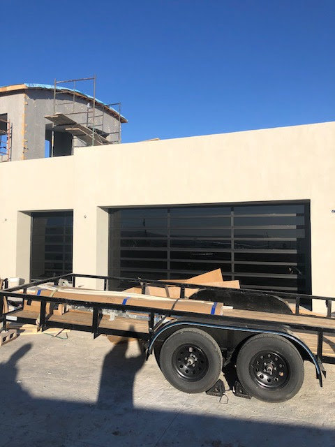Two new black garage doors with horizontal windows installed on a house under construction by Quality-Brand Garage Doors in Rio Rancho, NM.